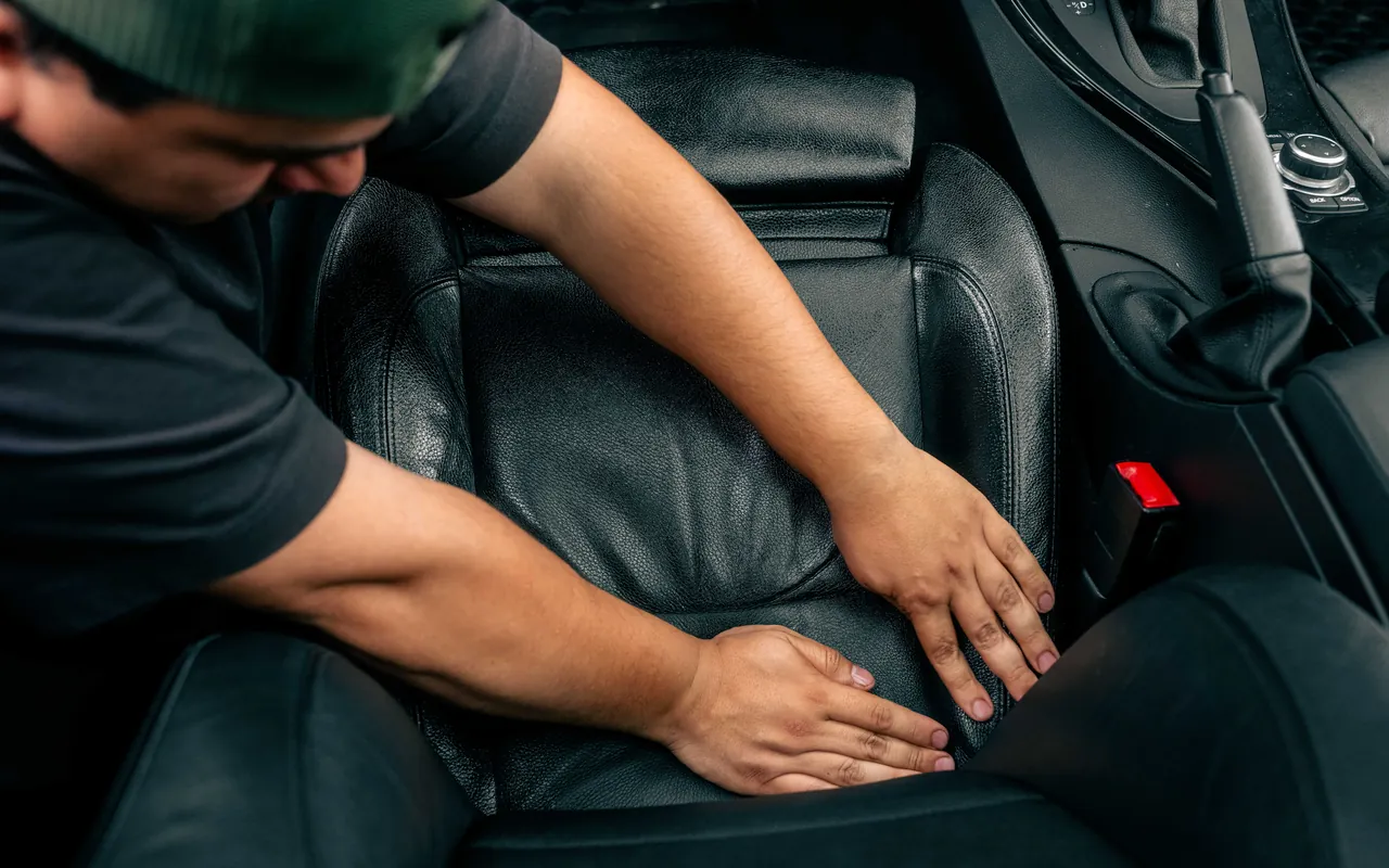 Johnnie massaging leather conditioner into a black leather seat by hand